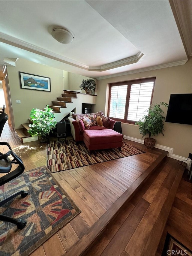 living room featuring hardwood / wood-style floors, ornamental molding, and a raised ceiling