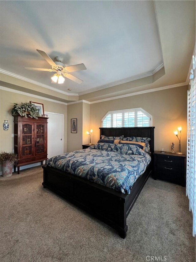 carpeted bedroom with ceiling fan, a tray ceiling, and crown molding