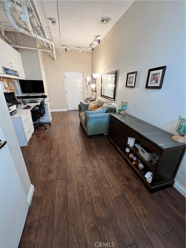 living room with dark hardwood / wood-style flooring and track lighting