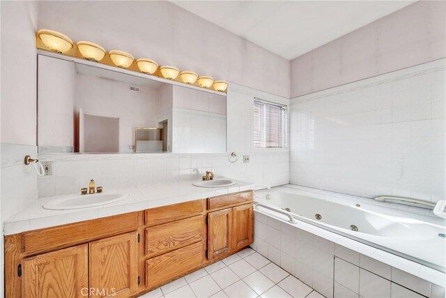 bathroom featuring tiled tub, tile patterned flooring, and vanity