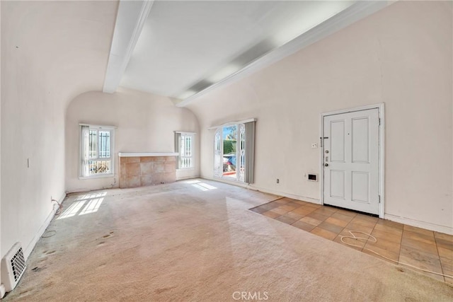 unfurnished living room with lofted ceiling with beams, light tile patterned floors, and a wealth of natural light