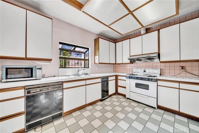 kitchen with white stove, white cabinets, sink, decorative backsplash, and black dishwasher