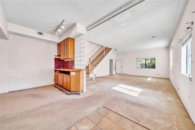 unfurnished living room featuring a textured ceiling and light colored carpet