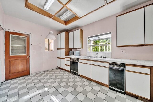 kitchen with white cabinets, dishwasher, pendant lighting, and sink