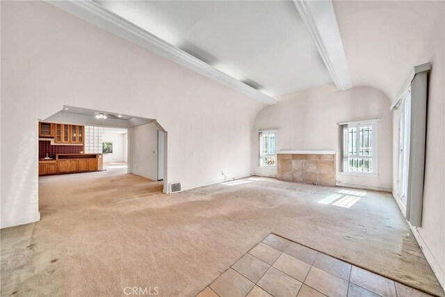 unfurnished living room with vaulted ceiling with beams, ceiling fan, and light colored carpet