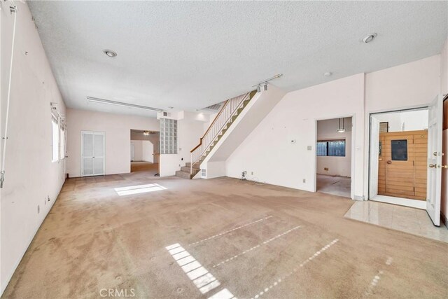 unfurnished living room featuring carpet and a textured ceiling