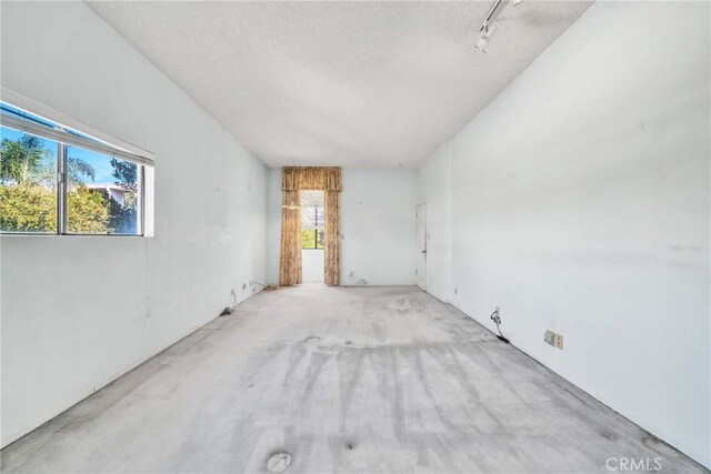 empty room featuring a textured ceiling and track lighting