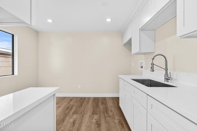 kitchen with white cabinetry, light hardwood / wood-style flooring, and sink