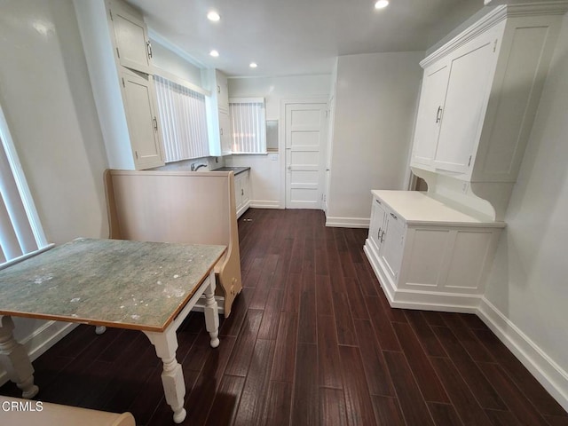 kitchen with kitchen peninsula, white cabinetry, dark hardwood / wood-style flooring, and a breakfast bar