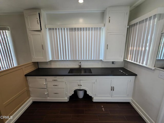 kitchen featuring dark hardwood / wood-style floors, white cabinetry, crown molding, and sink