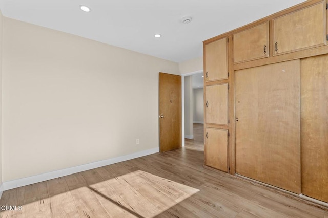 unfurnished bedroom featuring light hardwood / wood-style flooring and a closet