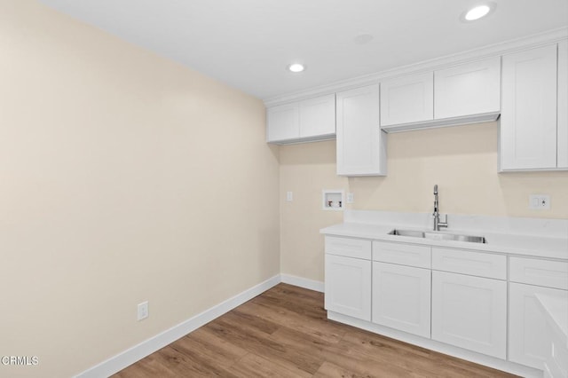 kitchen featuring white cabinets, light wood-type flooring, and sink