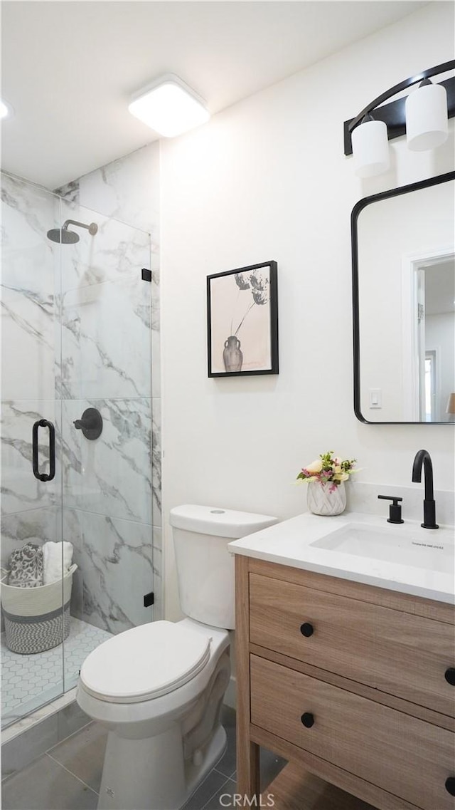 bathroom featuring toilet, vanity, tile patterned flooring, and a shower with shower door