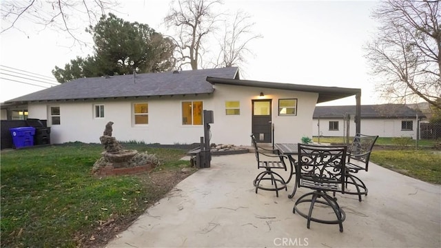 back of property with a lawn and a patio