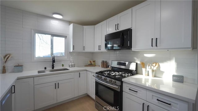 kitchen featuring decorative backsplash, stainless steel gas stove, sink, and white cabinetry