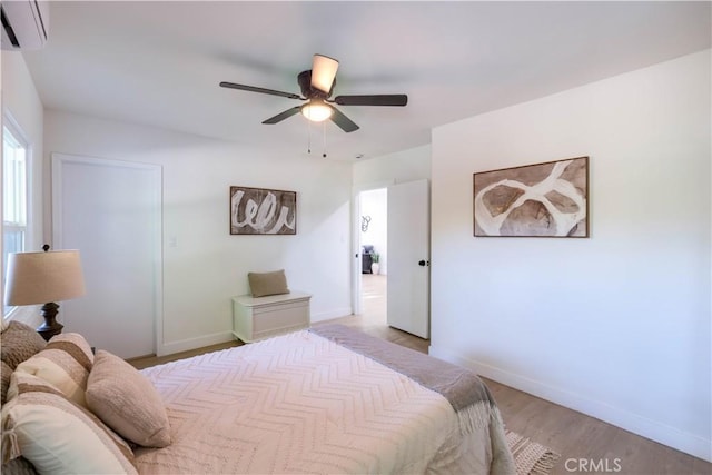 35414 Date Ave, Yucaipa, CA 92399 - bedroom featuring a wall mounted AC, light wood-style flooring, and a ceiling fan