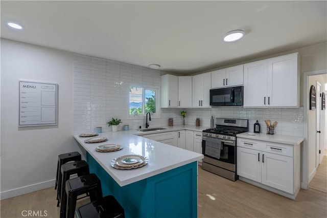 35414 Date Ave, Yucaipa, CA 92399 - kitchen featuring black microwave, gas range, a kitchen breakfast bar, decorative backsplash, and white cabinets