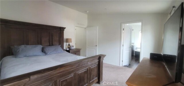 bedroom featuring ensuite bathroom, light colored carpet, and vaulted ceiling