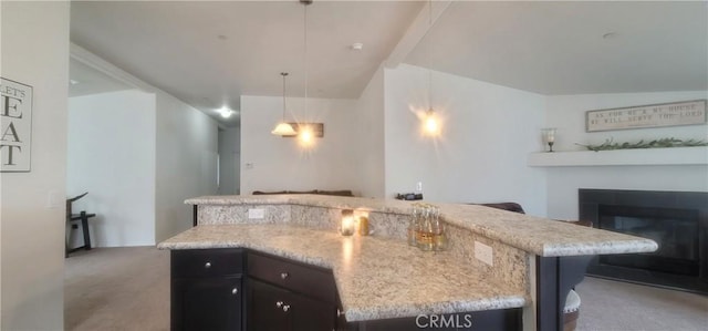 kitchen featuring pendant lighting, vaulted ceiling, a kitchen island, and light stone counters