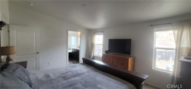 bedroom featuring ensuite bathroom and lofted ceiling