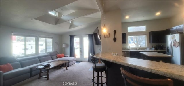 kitchen with light carpet, stainless steel fridge, a breakfast bar, vaulted ceiling, and sink