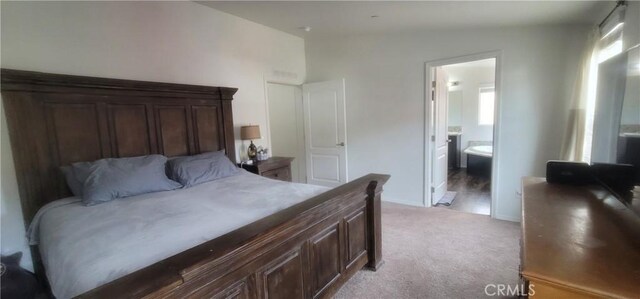 bedroom with light carpet, vaulted ceiling, and ensuite bath