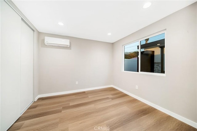 empty room featuring a wall mounted air conditioner and wood-type flooring