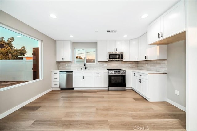 kitchen with white cabinets, stainless steel appliances, light hardwood / wood-style flooring, and sink