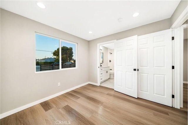 unfurnished bedroom with light wood-type flooring and ensuite bath