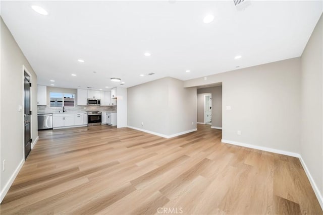 unfurnished living room featuring light hardwood / wood-style flooring and sink