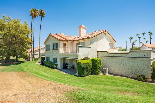 back of property with a lawn and a balcony