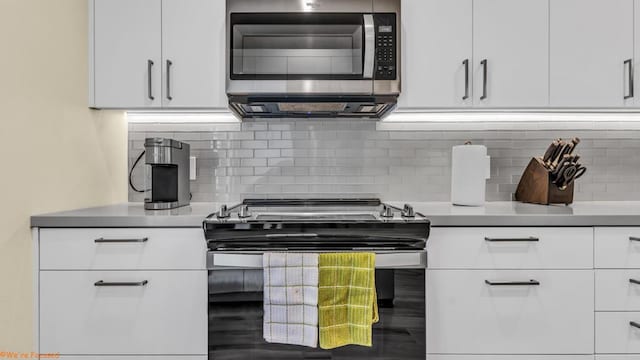 kitchen with decorative backsplash, white cabinetry, and black range with electric cooktop