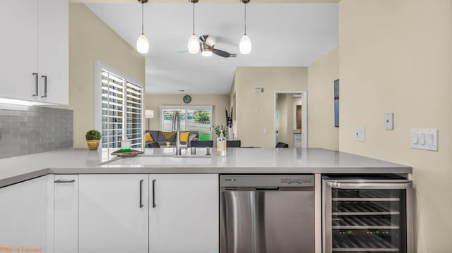 kitchen with stainless steel dishwasher, white cabinetry, backsplash, and beverage cooler