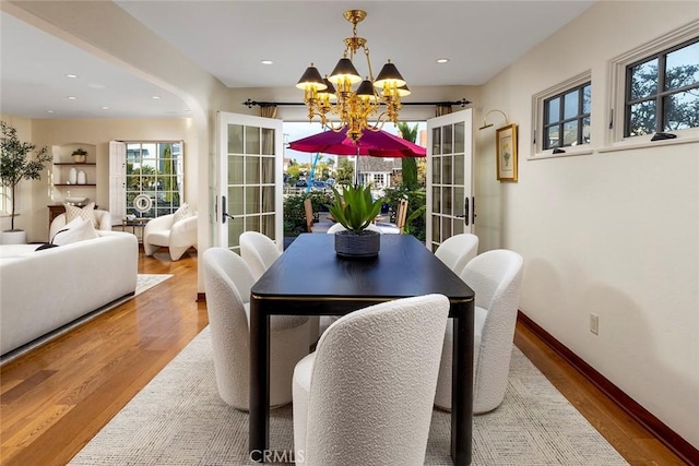 dining room featuring hardwood / wood-style floors, french doors, and a chandelier