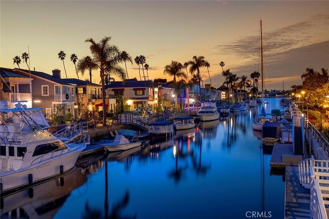 pool at dusk with a boat dock and a water view