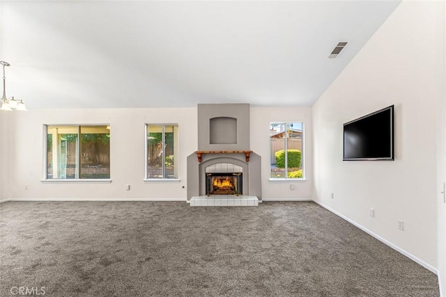 unfurnished living room featuring carpet flooring, a chandelier, a tiled fireplace, and vaulted ceiling