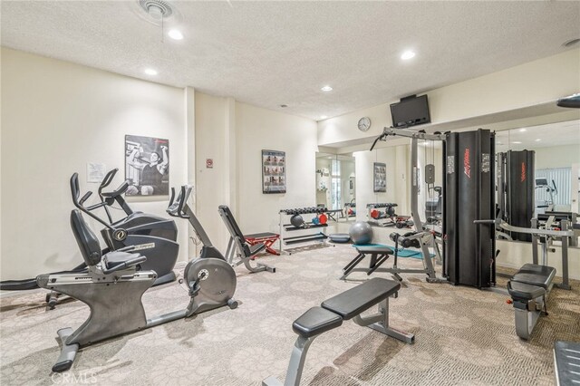 exercise room featuring light colored carpet and a textured ceiling