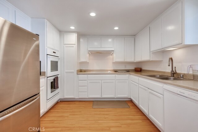 kitchen with sink, white appliances, light hardwood / wood-style floors, and white cabinets