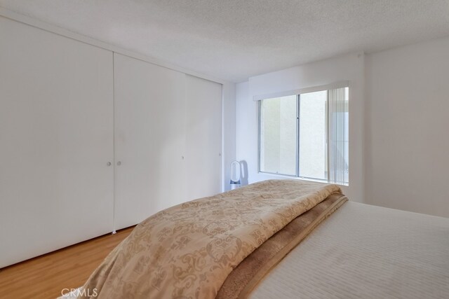 bedroom with hardwood / wood-style flooring, a closet, and a textured ceiling