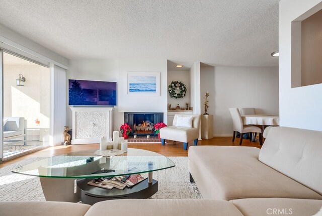 living room with a brick fireplace, hardwood / wood-style floors, and a textured ceiling