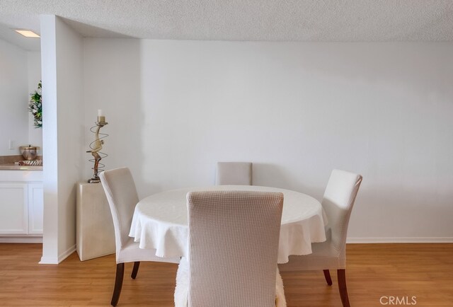 dining area featuring a textured ceiling and light wood-type flooring