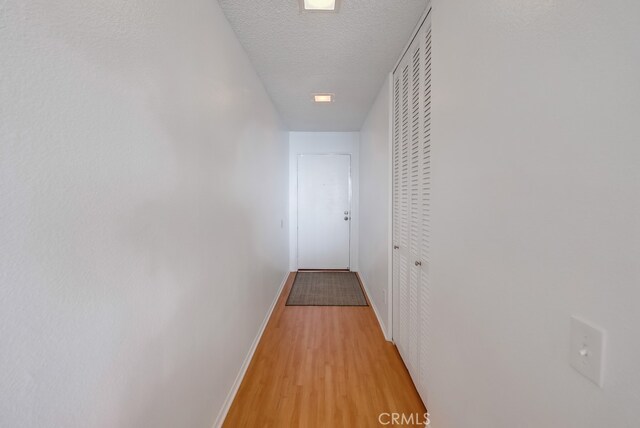 hallway featuring a textured ceiling and light hardwood / wood-style floors