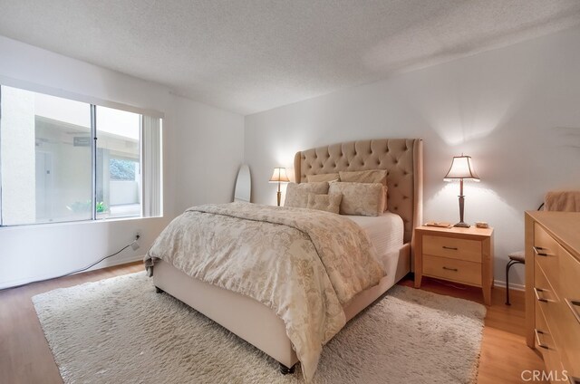 bedroom with a textured ceiling and light hardwood / wood-style flooring