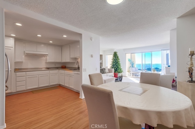 dining room featuring sink, a textured ceiling, and light wood-type flooring