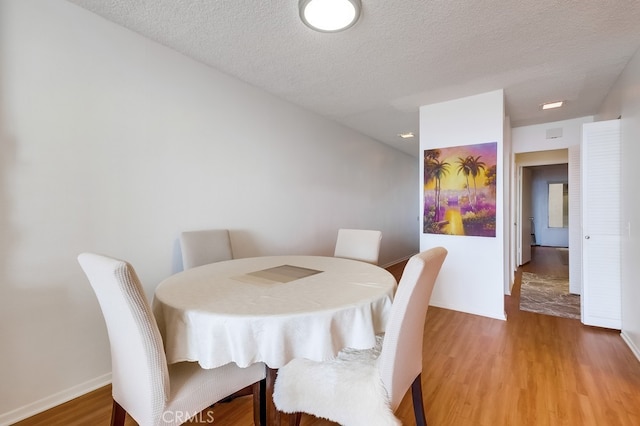 dining space featuring wood-type flooring and a textured ceiling