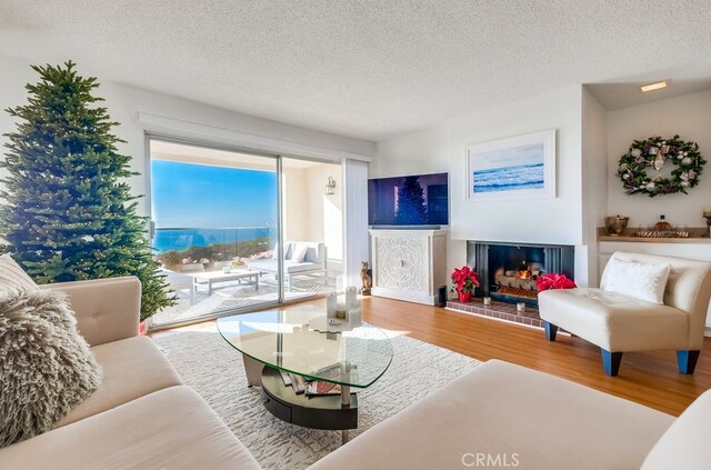 living room featuring a brick fireplace, hardwood / wood-style flooring, and a textured ceiling