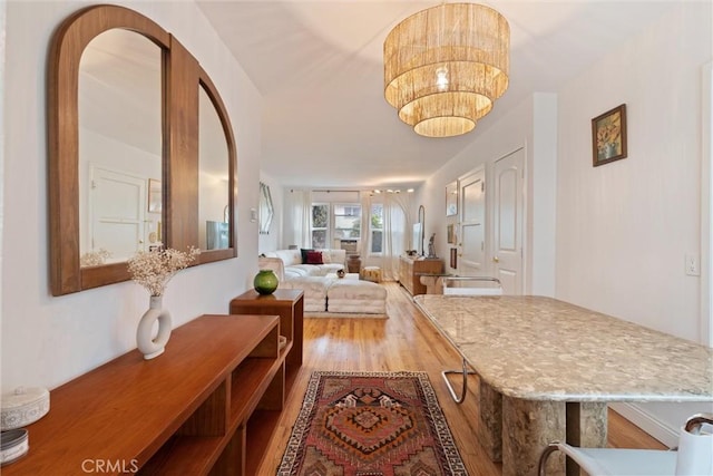 corridor featuring an inviting chandelier and hardwood / wood-style flooring