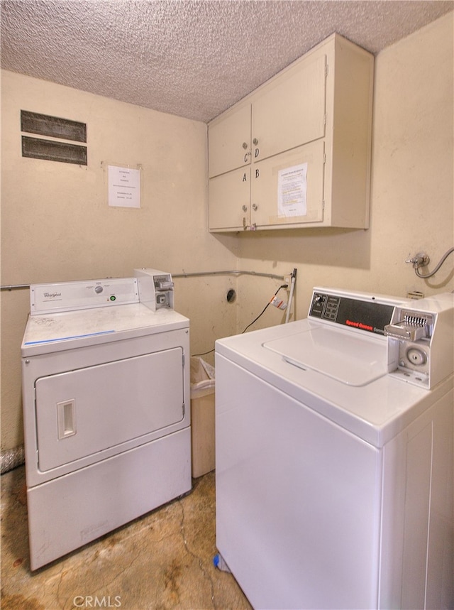 clothes washing area with separate washer and dryer and a textured ceiling