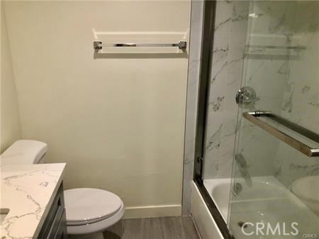 full bathroom with hardwood / wood-style floors, vanity, toilet, and shower / bath combination with glass door