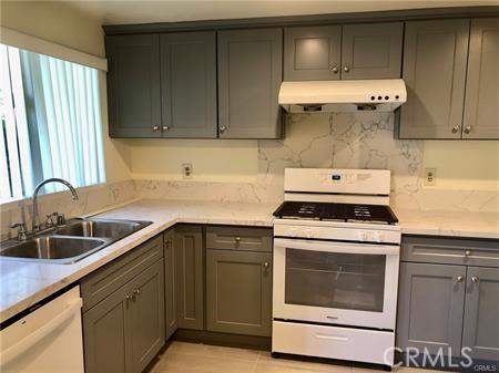 kitchen with gray cabinetry, decorative backsplash, white appliances, and sink